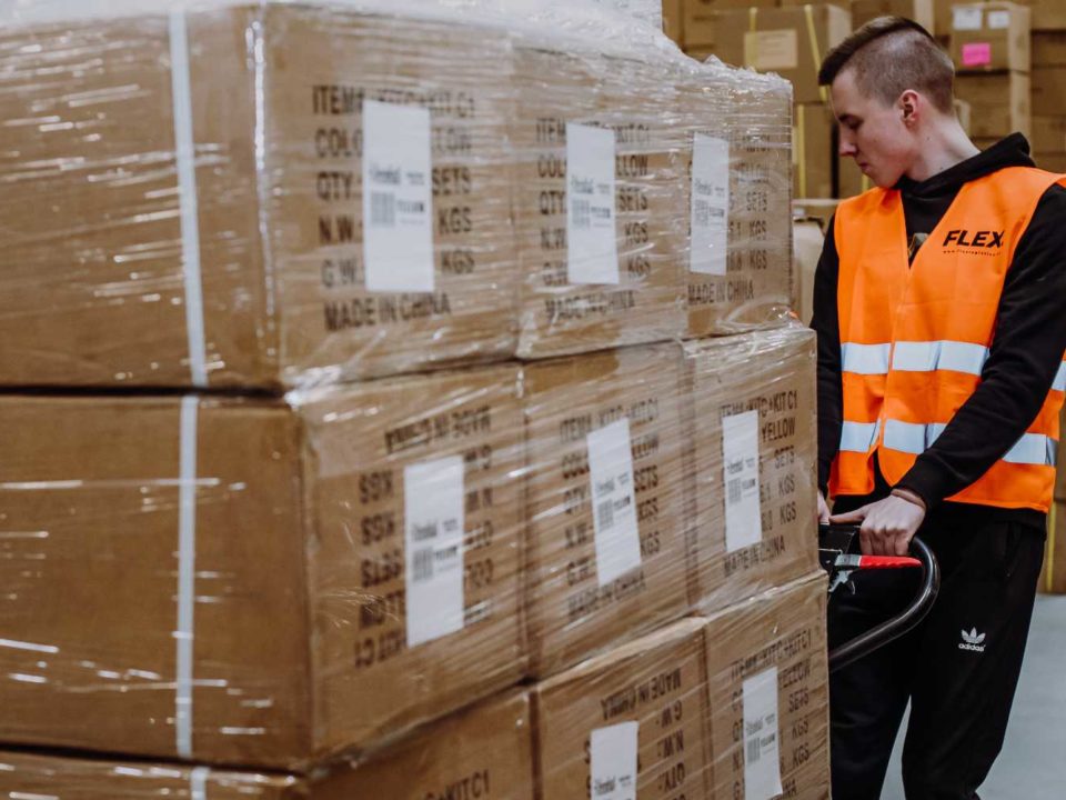 FLEX warehouse worker pulling a cart with packed boxes