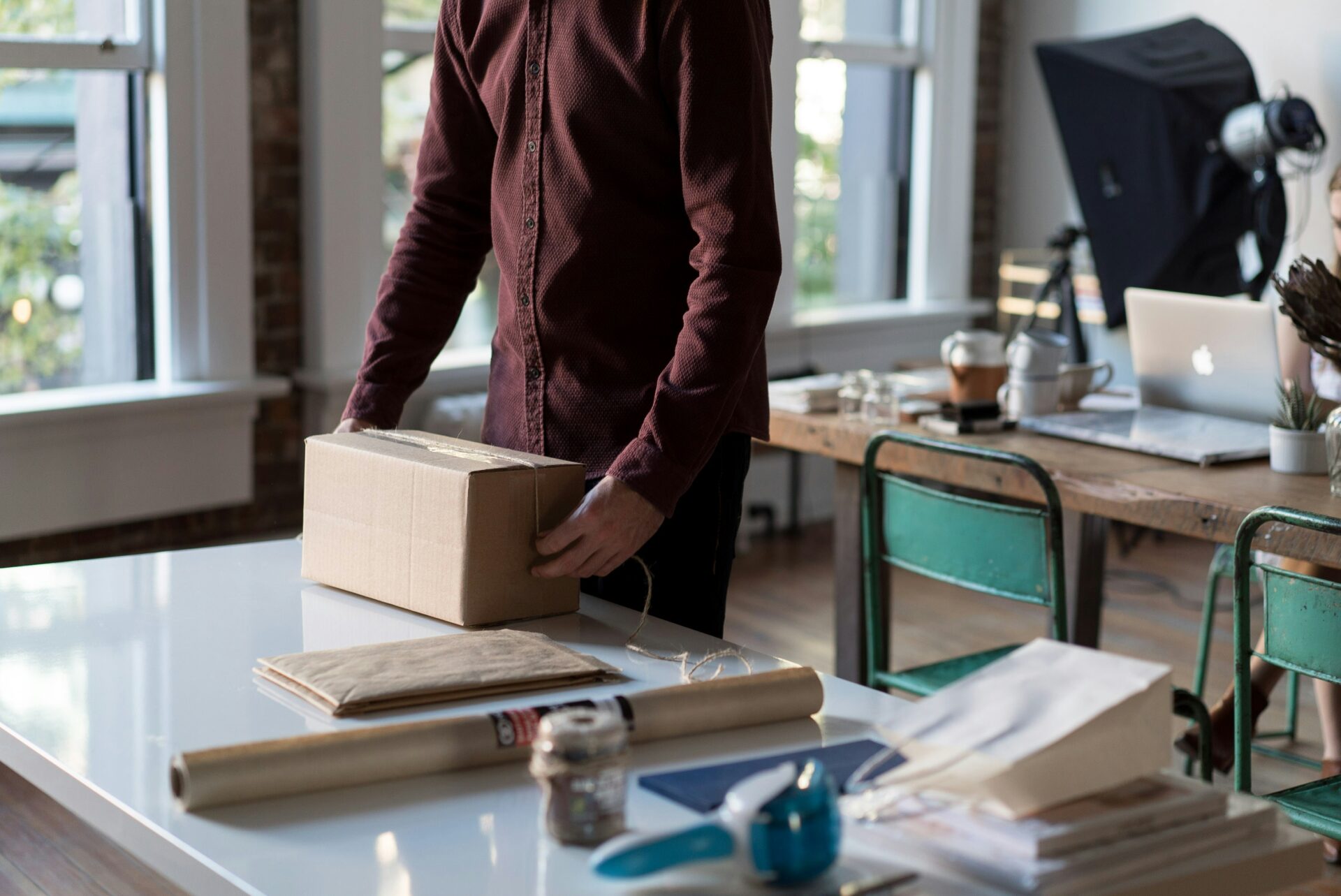 Man packing an e-commerce parcel in a warehouse, preparing shipment as part of efficient order fulfillment process