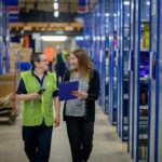 Two women walking through a warehouse managing inventory and e-commerce stock