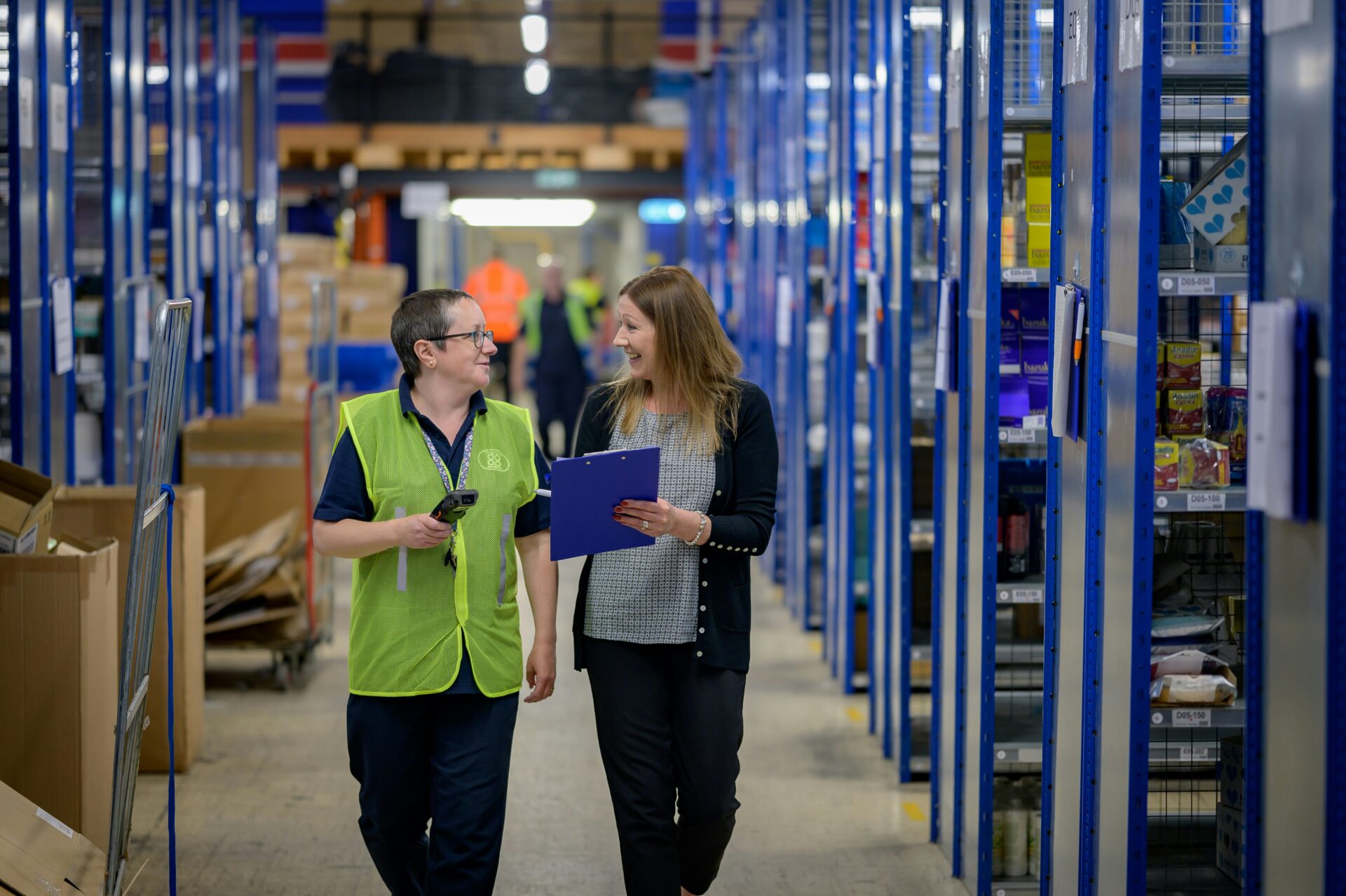 Two women walking through a warehouse managing inventory and e-commerce stock