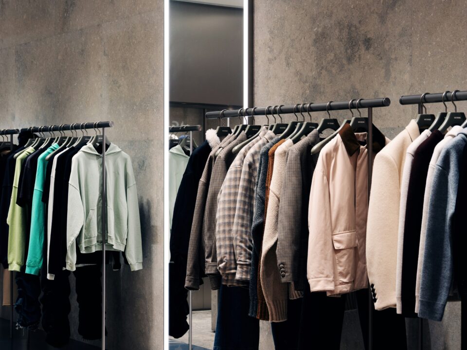 Clothes on racks inside of a modern apparel retailer.