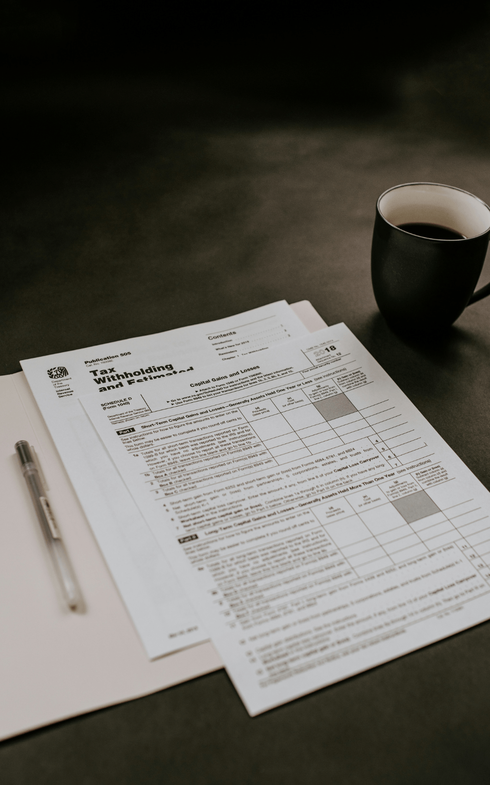 Printed tax documents and a pen on a desk beside a cup of coffee, representing the administrative complexity of VAT and customs paperwork that smart fulfillment processes help automate for EU cross-border operations.
