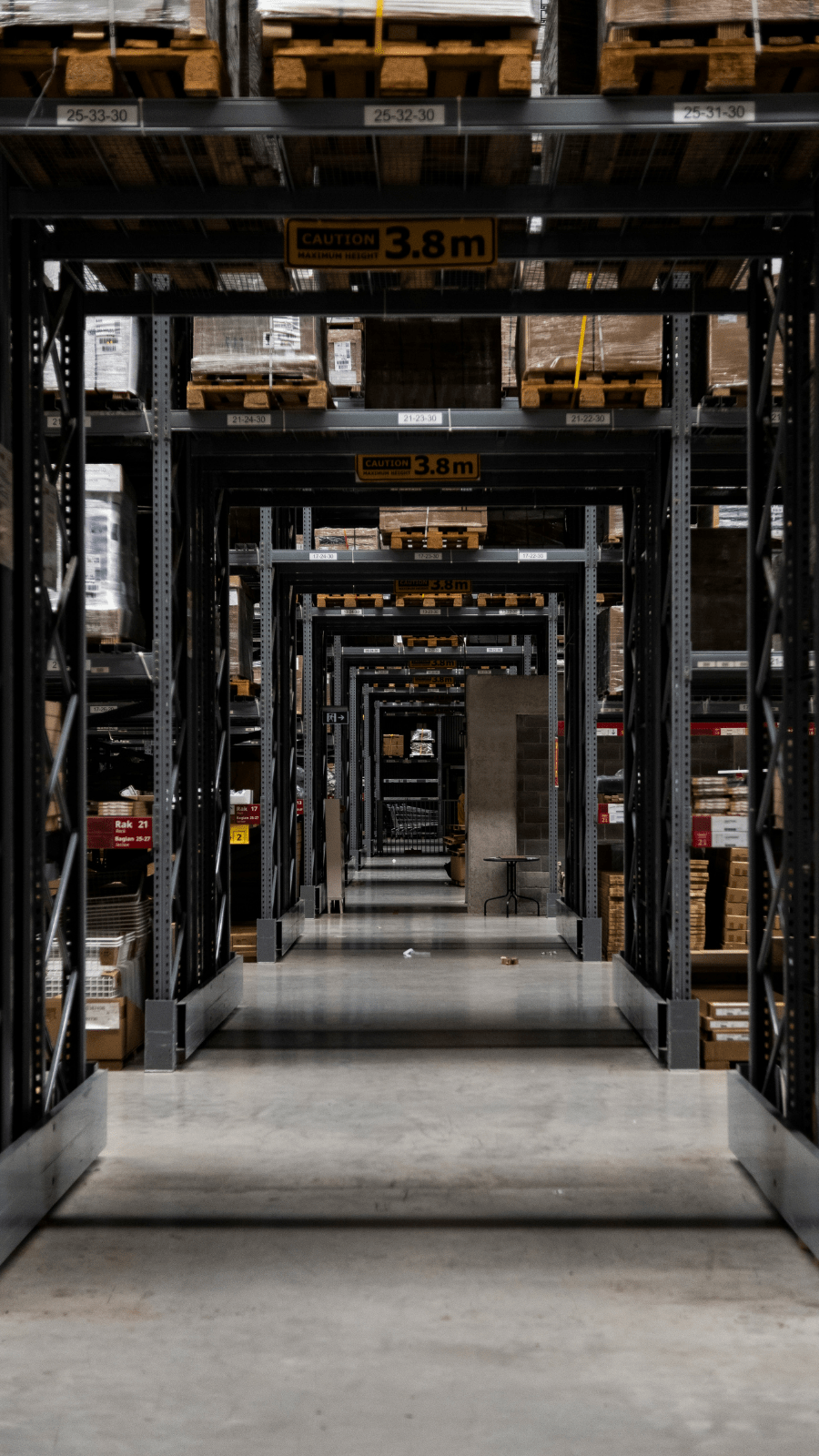 A long warehouse aisle with high industrial shelving, representing the importance of strategically located fulfillment centers for fast and reliable delivery across Europe.