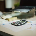 Calculator and documents on a modern office desk with a laptop and keyboard.