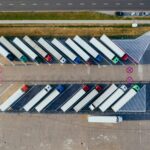 Aerial view of semi-trucks parked diagonally in a large lot.