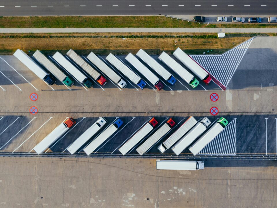 Aerial view of semi-trucks parked diagonally in a large lot.