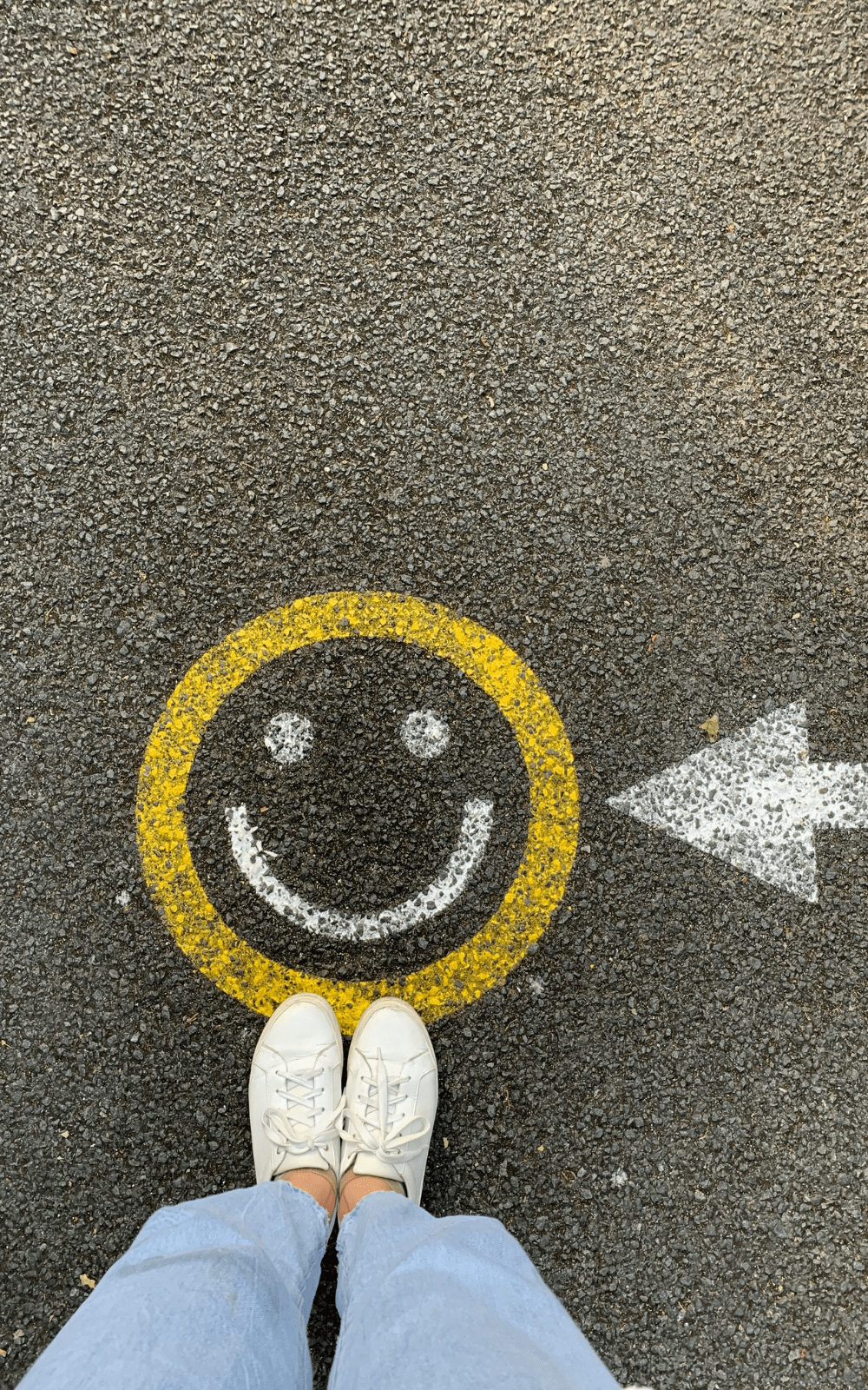 Person standing by a smiley symbol on pavement, representing customer satisfaction and the positive emotional impact of fast, reliable fulfillment.