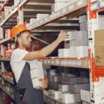 Warehouse worker restocking shelves to prepare for peak season order volume.