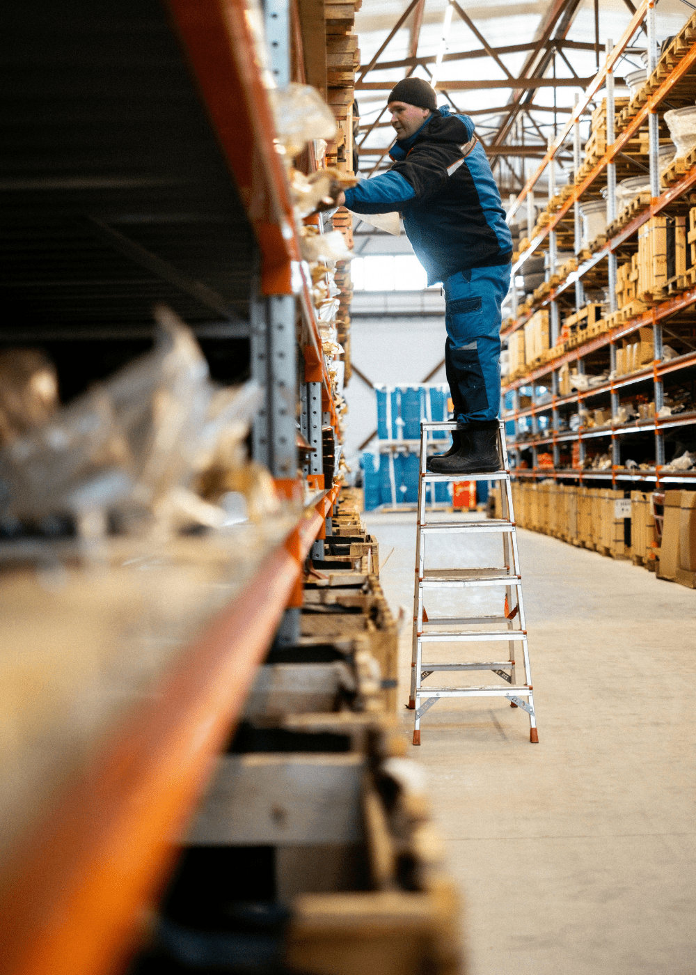 Warehouse worker organizing inventory on high shelves, illustrating structured, enterprise-level supply chain processes that support scalable e-commerce fulfillment.