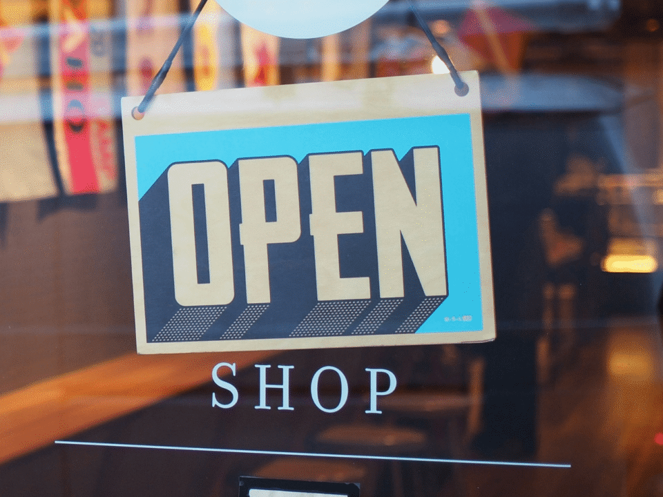Open sign displayed in a shop window, symbolizing a pop-up store as part of a phygital retail strategy connecting physical retail with online order fulfillment.