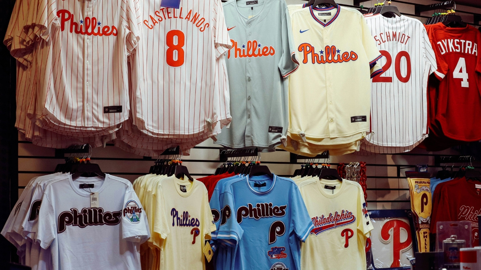 Sports jerseys and team apparel displayed on racks inside a retail store, showing multiple sizes and product variations.
