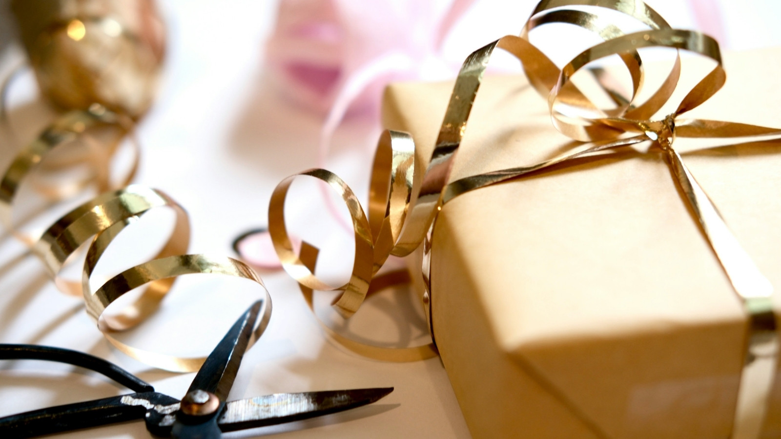 Gold gift box wrapped with ribbon and scissors on a packing table, representing personalized packaging preparation in e-commerce fulfillment.