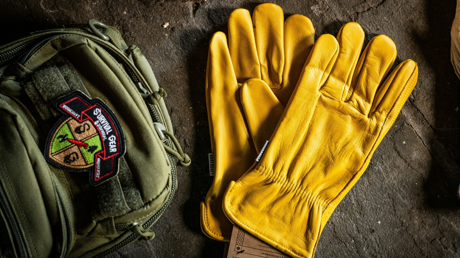 Yellow leather work gloves placed beside outdoor equipment, highlighting premium outdoor and adventure gear products.