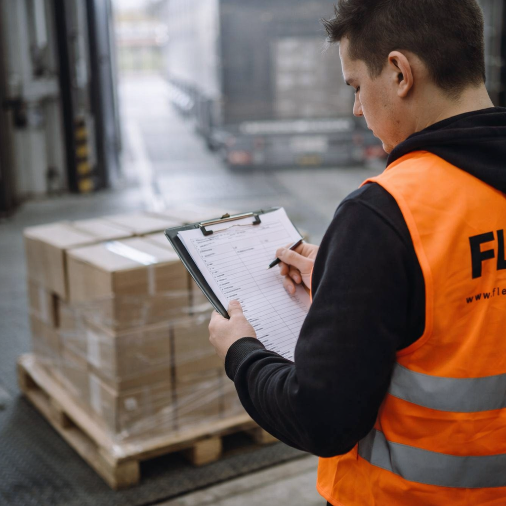 FLEX. logistics worker checking a received shipment against a packing list at a warehouse loading dock