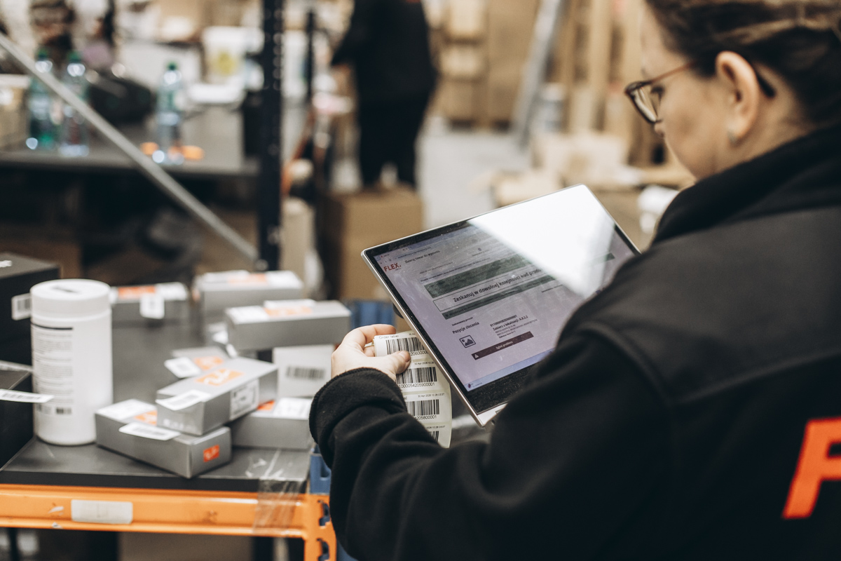 Membro da equipa de armazém da FLEX a usar um tablet para gerir inventário e operações de fulfillment