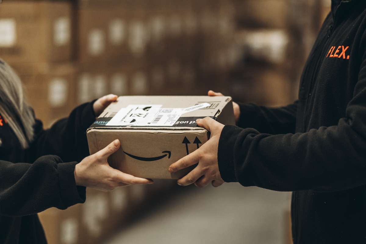 FLEX Two warehouse team members handing over a parcel